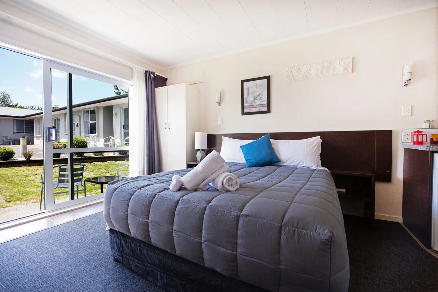 Bedroom with a double bed and garden-facing doors at Lake Breeze Motel